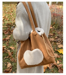 Close-up of brown suede tote bag featuring white lamb wool heart patch and drawstring detail