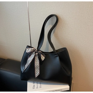Detail view of black matte leather tote bag featuring a decorative printed silk scarf on handle