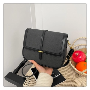 Close-up of black textured fabric crossbody bag with leather trim and gold buckle detail