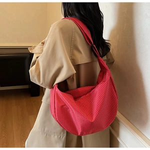 Borsa a tracolla a quadretti rossi a forma di mezzaluna indossata con un trench coat