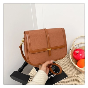 Detail of caramel woven texture crossbody bag with gold metallic buckle and leather trim