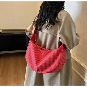 Dettaglio di una borsa hobo in tela a quadretti rossi e bianchi indossata a tracolla moda