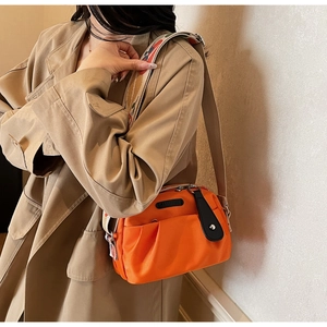 Detail of orange nylon crossbody bag with pleated pocket and colorful jacquard strap