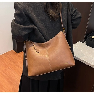 Brown leather large tote bag with adjustable strap and logo shown on a person