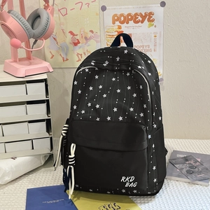 Detail of black backpack with white star patterns and RKD BAG logo in a student study desk setup