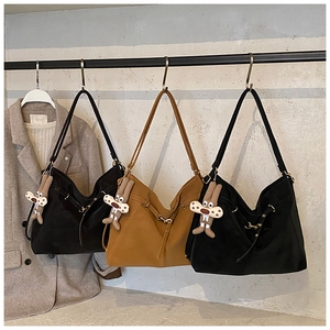 Close-up of leather tote bags with metal buckles and cute rabbit pendants on a metal rack