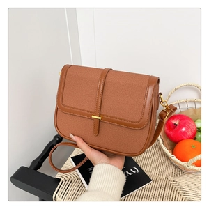 Detail view of brown leather and canvas crossbody bag with elegant gold buckle hardware