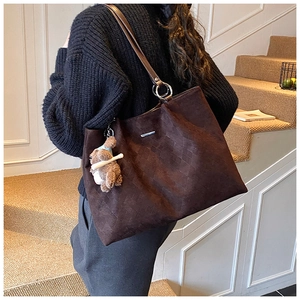 Detail of dark brown tote bag featuring quilted texture and cute bear plush charm