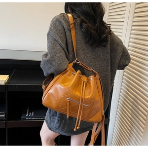 Détail d'un sac seau matelassé marron avec cordon de serrage et poche zippée à l'avant