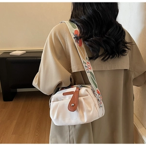 Detail of off-white crossbody bag with vintage floral embroidery on wide strap