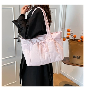 Détail d'un sac cabas matelassé rose avec poche à cordon sur un mannequin en manteau noir