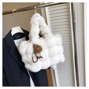 Détail d'un sac cabas en fausse fourrure blanche avec un pendentif pompon marron doux