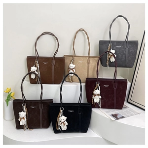 Multiple textured leather tote bags in various colors displayed with plush bear charms