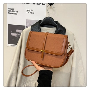 Close-up of brown textured fabric and leather crossbody bag held by a model