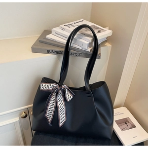 Detailed view of black leather tote bag with geometric silk scarf on a cream background