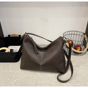 Detailed macro view of deep brown leather texture with white contrast stitching on tote bag