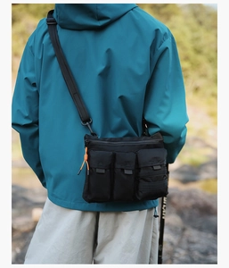 Outdoor tactical crossbody bag in black nylon with three pockets and orange paracord details