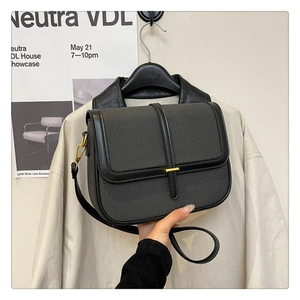 Detail of grey twill crossbody bag with black leather trim and golden metal clasp