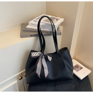 Detail of black matte PU leather tote bag with a geometric silk scarf on a sofa