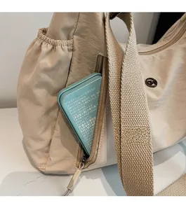Détail du sac à bandoulière en toile beige avec poche zippée verticale fonctionnelle