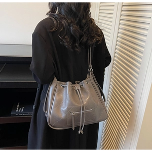 Sac seau matelassé gris-violet avec cordon de serrage et poche zippée porté à l'épaule