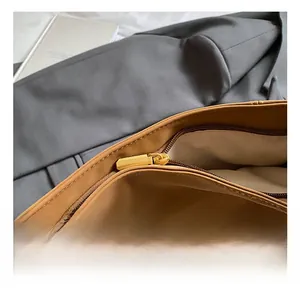 Detail view of golden metal zipper and durable fabric lining on brown tote bag