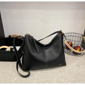 Detail view of the black leather tote bag featuring gold LYSMN logo and adjustable strap