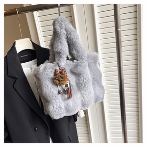 Détail du sac cabas en fausse fourrure grise avec un charm léopard sur un cintre mode