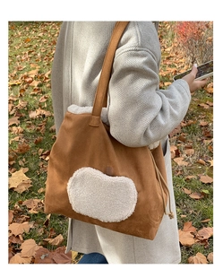 Brown suede tote bag with white fleece apple patch shown in an outdoor autumn setting