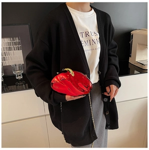 Close-up of a glossy red acrylic evening bag with gold chain and irregular shell design