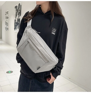 Détail du sac bandoulière en nylon à carreaux gris avec sangle sur mannequin urbain