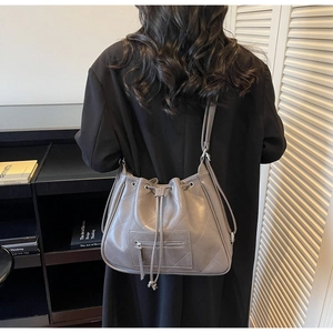 Détail du sac seau matelassé gris avec cordon de serrage et poche frontale zippée