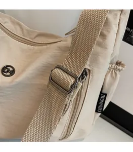 Détail de la bandoulière réglable et boucle en métal sur sac beige en nylon
