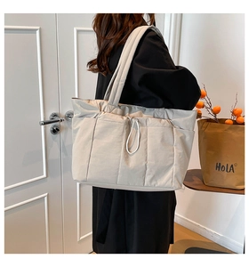 Détail d'un grand sac cabas en nylon abricot clair avec texture matelassée et poches