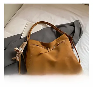 Detail show of caramel faux leather tote with buckle strap and plush dog pendant