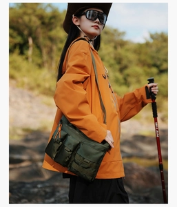 Detail showing outdoor tactical crossbody bag with multiple pockets and orange zipper accents