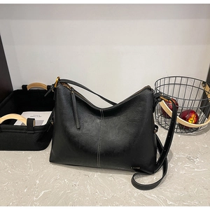 Detail of minimalist black leather tote bag with gold brand logo and vertical stitching