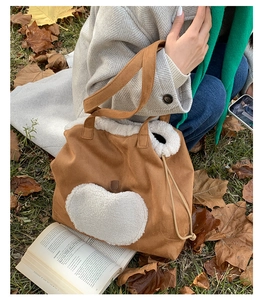 Detail of suede tote bag featuring fuzzy apple patch and drawstring fleece trim details