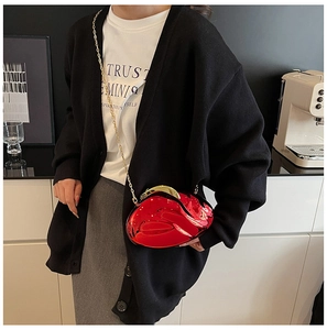 Detailed view of glossy red lip-shaped clutch bag with golden chain strap on a model