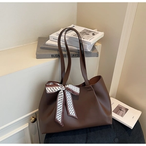 Close-up of large brown leather tote bag featuring decorative floral silk scarf on handle