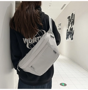 Détail du sac bandoulière en nylon quadrillé gris clair porté par un mannequin urbain