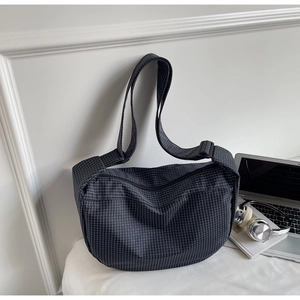Foto lifestyle della borsa a mezzaluna a scacchi neri con tracolla e laptop accanto