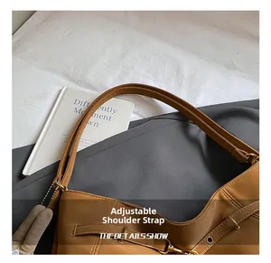 Detail shot of the adjustable shoulder strap with metal buckle on the caramel brown tote bag