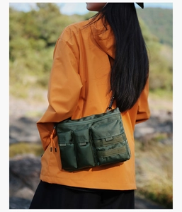 Detail of outdoor crossbody bag with multiple pockets and nylon texture on a model
