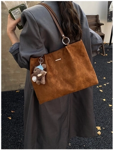 Detail of brown suede tote bag with diamond lattice texture and cute baseball bear charm