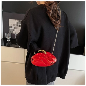 Detailed view of a red heart-shaped acrylic evening bag with gold chain and handle