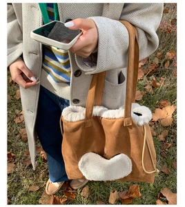 Brown faux suede tote bag with cream fleece heart patch and drawstring detail in autumn setting