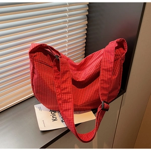 Dettaglio della borsa hobo in tela a scacchi rossi con tracolla regolabile su davanzale