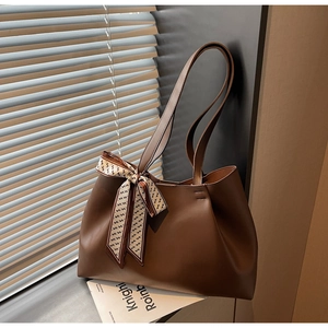 Brown leather tote bag with stylish decorative scarf shown in warm natural sunlight