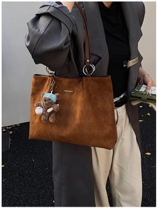Detail of brown faux suede tote bag with diamond texture and cute teddy bear charm